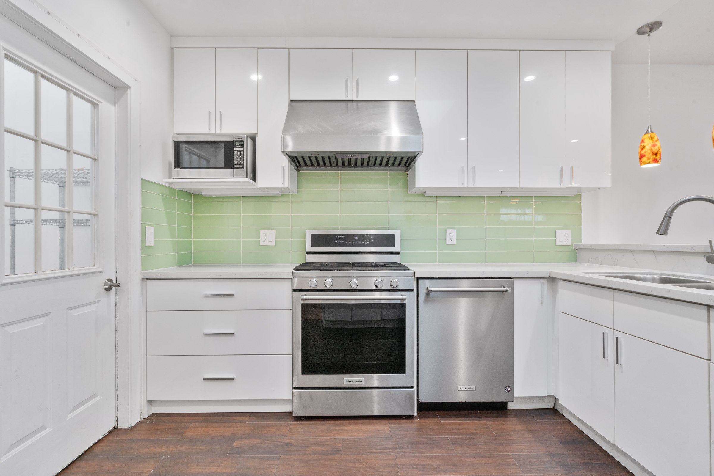 White cabinetry, green backsplash and stainless steel appliances