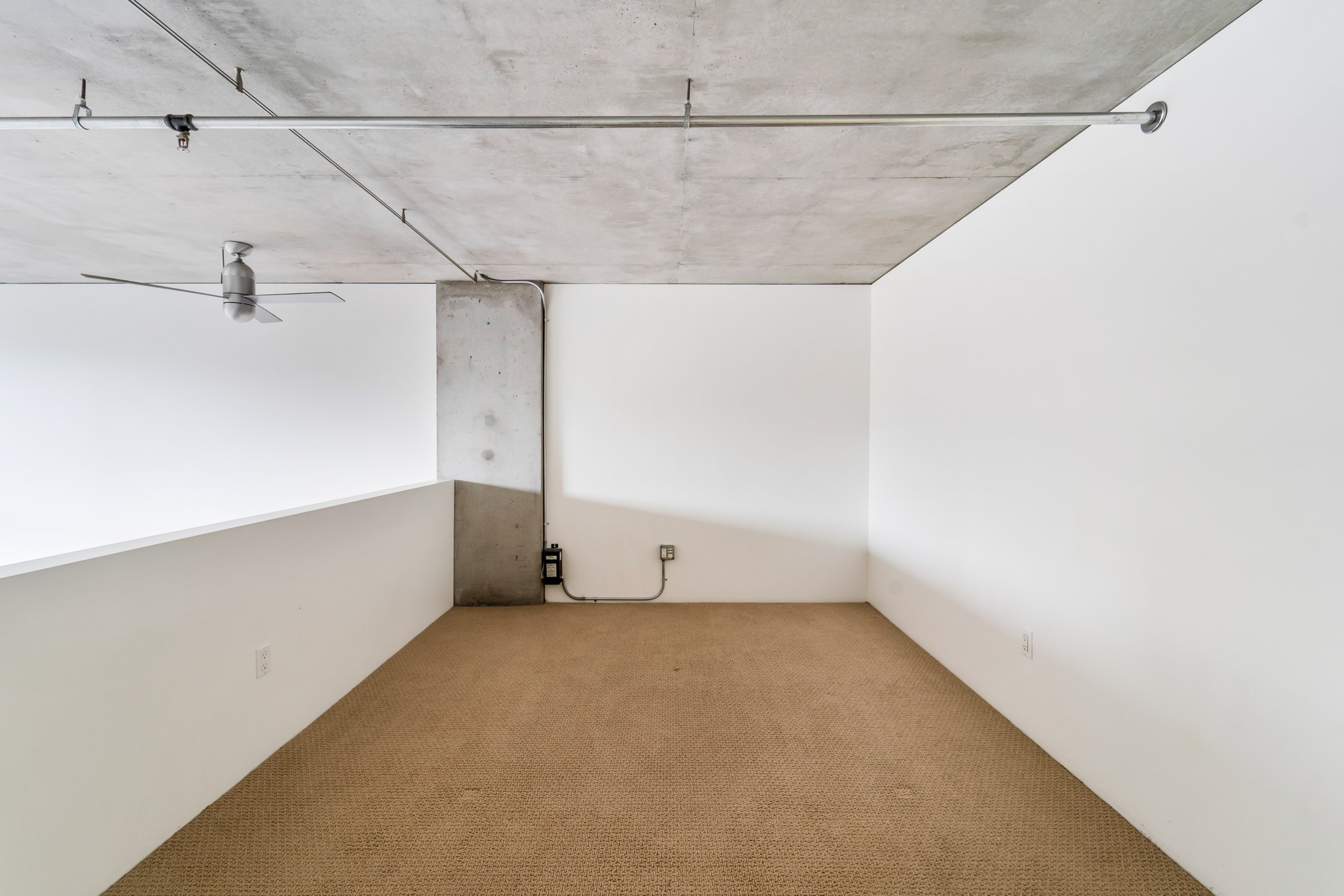 Loft bedroom beneath exposed concrete ceiling
